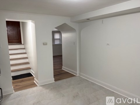 A spacious room with a staircase leading to a landing with a door.