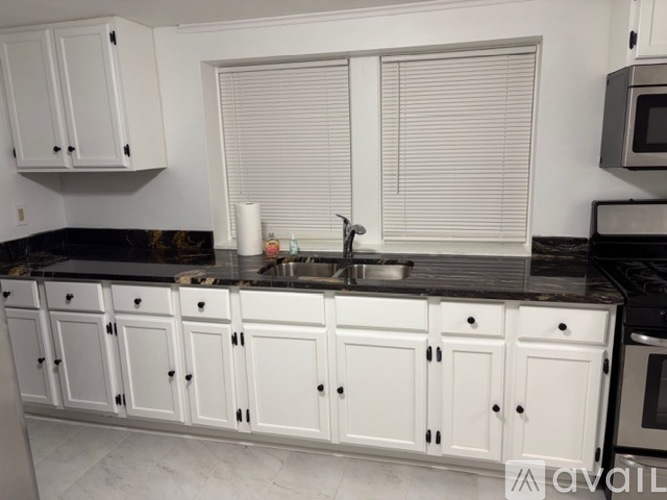 A kitchen with white cabinets and a black countertop.