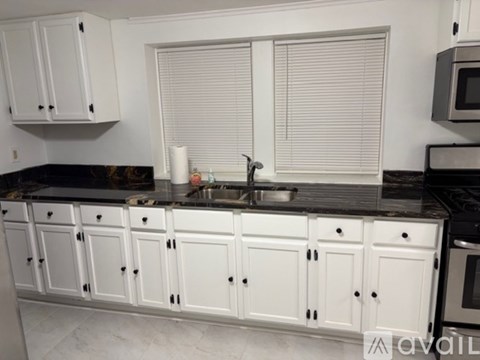 A kitchen with white cabinets and a black countertop.