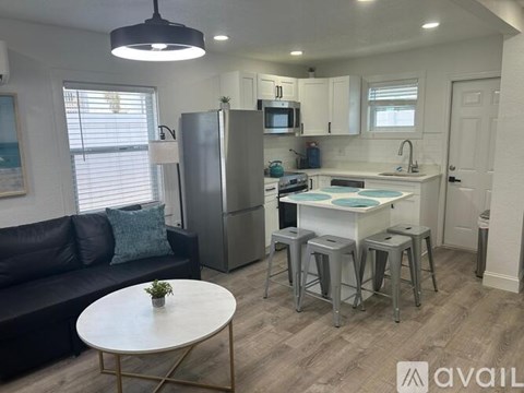 A modern kitchen with a refrigerator, stove, and bar stools.