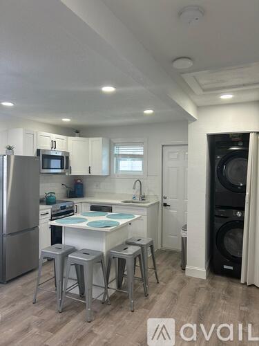 A kitchen with a refrigerator, stove, and washing machine.