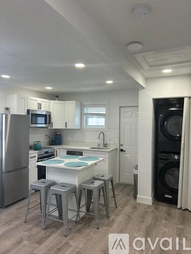 A kitchen with a refrigerator, stove, and washing machine.