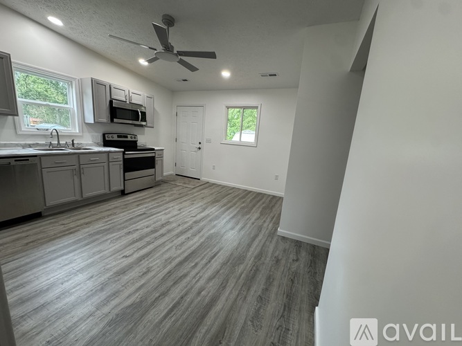 A spacious kitchen with grey flooring and a ceiling fan.