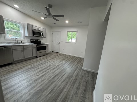 A spacious kitchen with grey flooring and a ceiling fan.