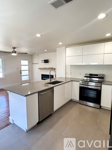 A modern kitchen with white cabinets and stainless steel appliances.