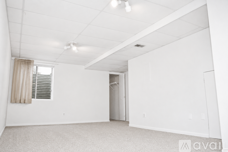 A spacious, empty room with a window and a door leading to another room.
