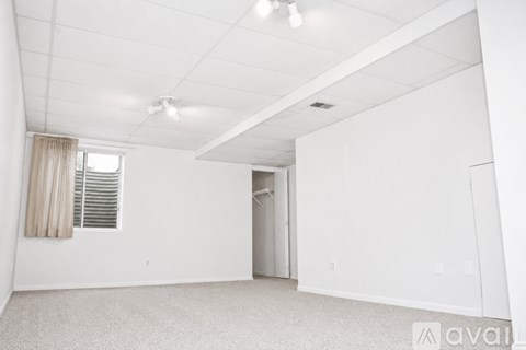 A spacious, empty room with a window and a door leading to another room.
