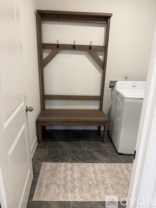 A laundry room with a washer and dryer and a bench.