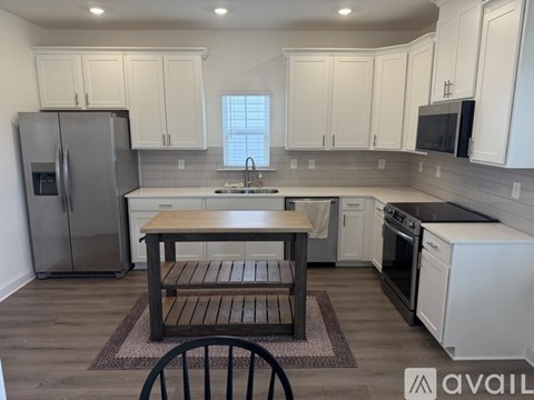 A kitchen with white cabinets and a wooden table.