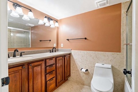 A bathroom with brown cabinets and a white toilet.