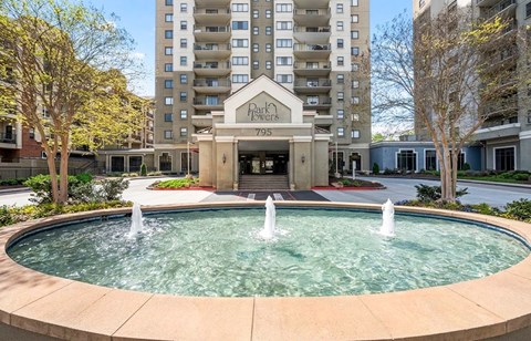 A fountain in the middle of a courtyard in front of a building with the name "Park Place" on it.