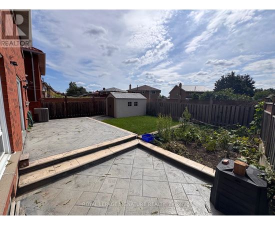 A backyard with a patio and a fence.