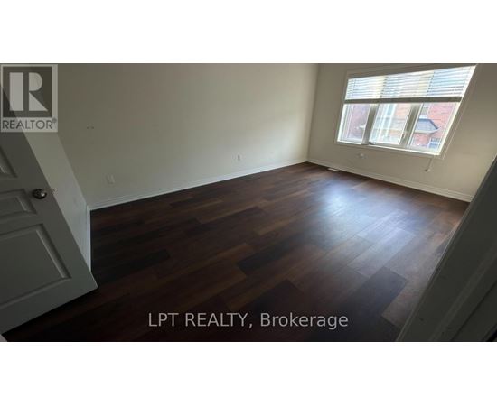 A room with wooden flooring and a window with blinds.