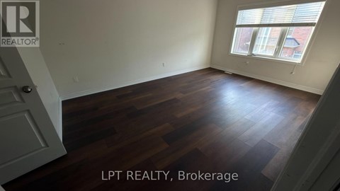 A room with wooden flooring and a window with blinds.