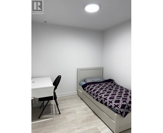 A bedroom with a bed, desk, and chair.