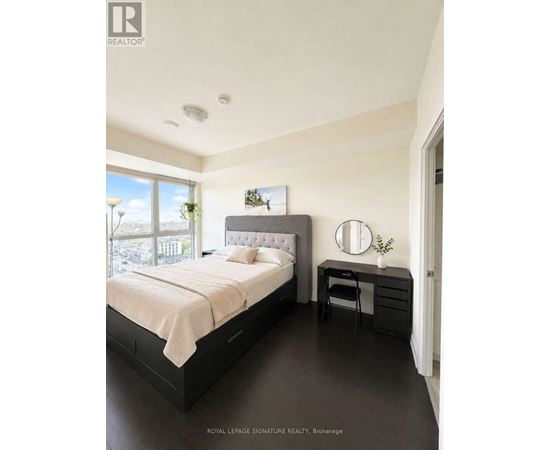 A bedroom with a large bed and a desk with a chair.