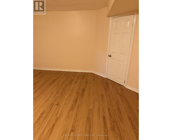 A room with a white door and wooden flooring.