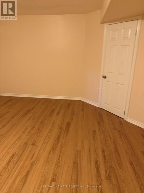 A room with a white door and wooden flooring.