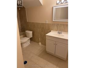 A bathroom with a toilet, sink, and mirror.
