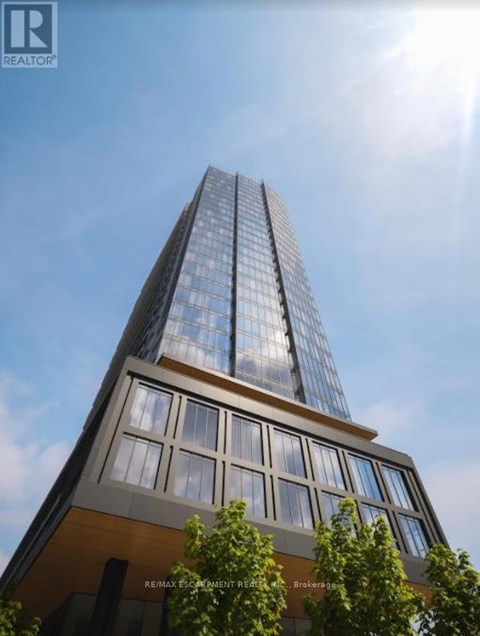 A tall building with a glass facade and a brown base is shown in the image.
