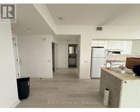 A kitchen area with a refrigerator, a counter, and a trash bin.