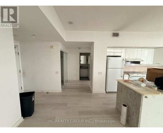 A kitchen area with a refrigerator, a counter, and a trash bin.