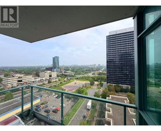 A view from a balcony overlooking a cityscape with a parking lot and buildings.
