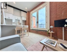 A living room with a grey sofa, a wooden coffee table, and a brick wall.