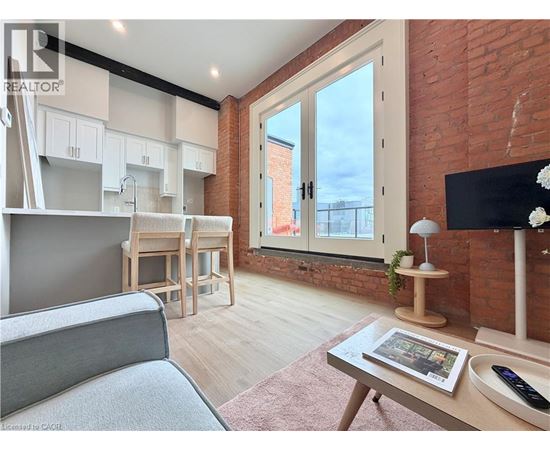 A living room with a grey sofa, a wooden coffee table, and a brick wall.