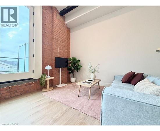 A living room with a grey couch, a wooden table, and a brick wall.
