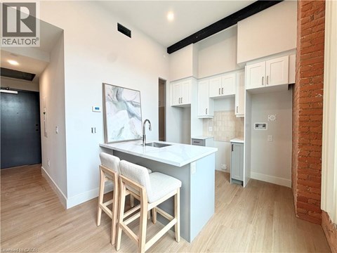 A kitchen with white cabinets and a brick wall.