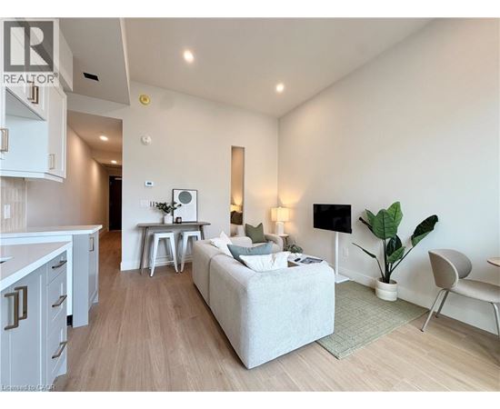 A well-lit, modern living room with a grey sofa and a wooden floor.