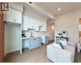 A well-lit kitchen with white cabinets and a grey couch.