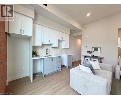 A well-lit kitchen with white cabinets and a grey couch.