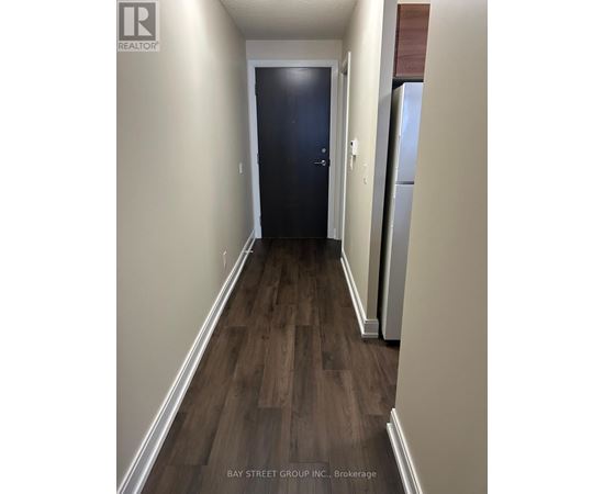 A hallway with a dark blue door and wooden flooring.