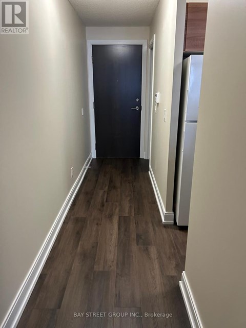 A hallway with a dark blue door and wooden flooring.