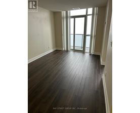 A room with wooden flooring and a view of the ocean through the windows.