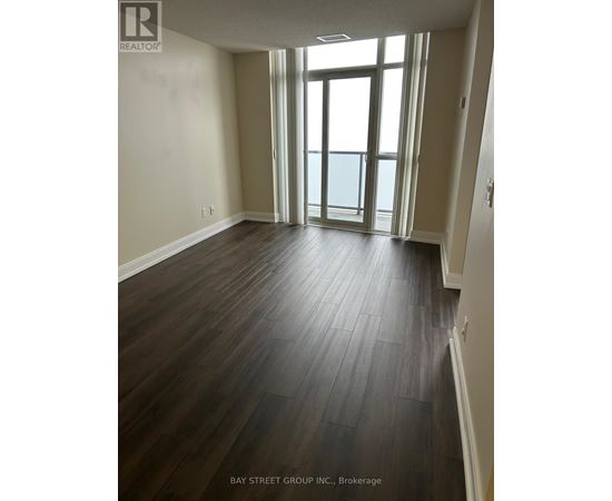 A room with wooden flooring and a view of the ocean through the windows.