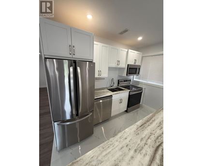 A modern kitchen with a stainless steel refrigerator and white cabinets.