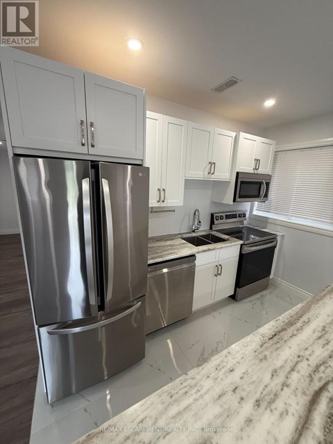 A modern kitchen with a stainless steel refrigerator and white cabinets.