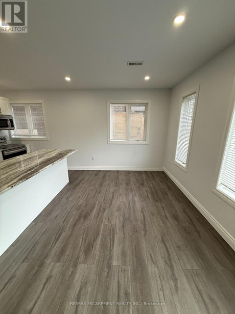 A room with a wooden floor and a window with blinds.