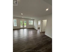 A spacious room with wooden flooring and white walls.
