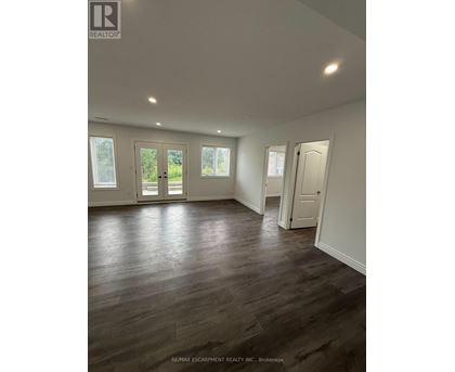 A spacious room with wooden flooring and white walls.