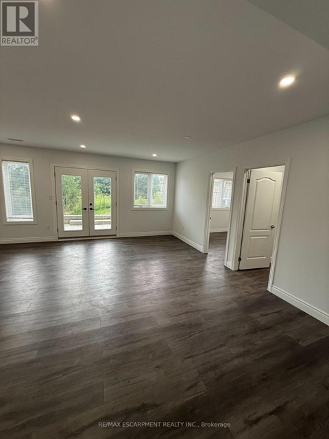 A spacious room with wooden flooring and white walls.