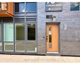 A building with a wooden door and a sign that says Curlew Drive.