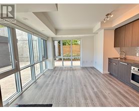 A spacious room with wooden flooring and large windows.