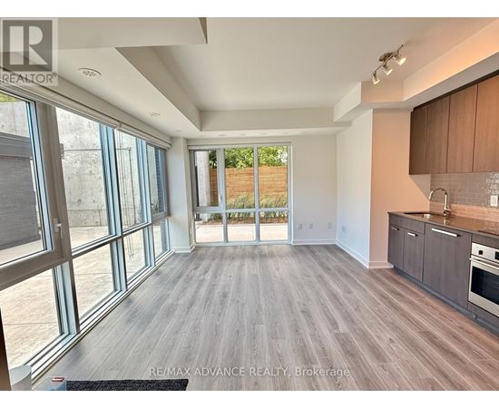 A spacious room with wooden flooring and large windows.