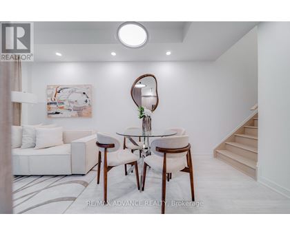A white living room with a couch, chair, and a painting on the wall.