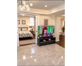 A bedroom with a bed, a nightstand, a TV, and a plant.