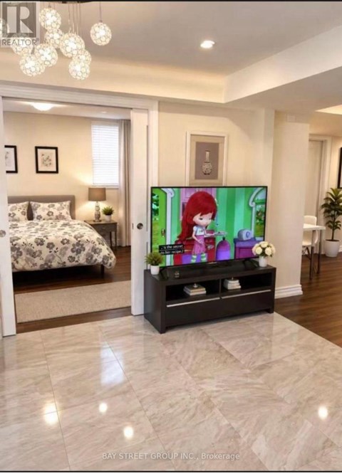 A bedroom with a bed, a nightstand, a TV, and a plant.